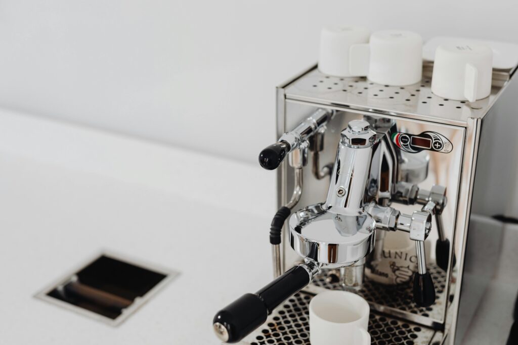 Sleek espresso machine on a white countertop with cups on top, perfect for any modern kitchen.
